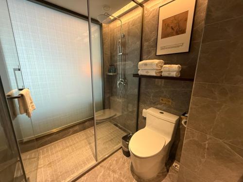 a bathroom with a toilet and a glass shower at Till Bright Hotel, Foshan Shunde Ronggui Station Branch in Shunde