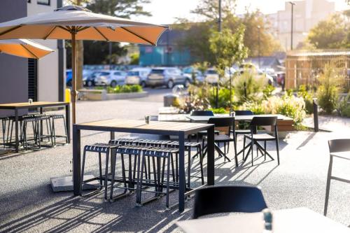 a group of tables and chairs with an umbrella at Hotel Give in Christchurch