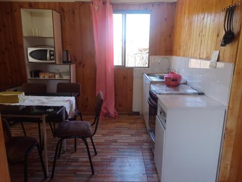 a kitchen with a sink and a table and a window at Cabaña Puipuyen Yerbas Buenas 