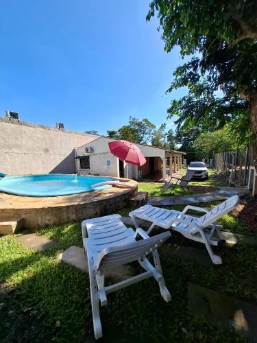 two lounge chairs and a pool with a red umbrella at Casa familiar estilo colonial a metros del lago in San Bernardino