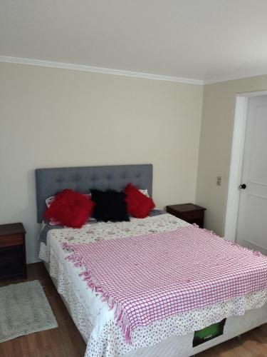 a bedroom with a bed with red pillows on it at Departamento A PASOS CASINO VIÑA in El Cerrillo