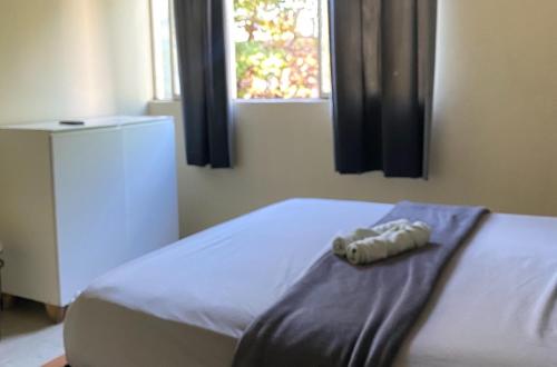 a bed with a towel on it with a window at Quarto Econômico no Centro para 2 Pessoas in Sete Lagoas
