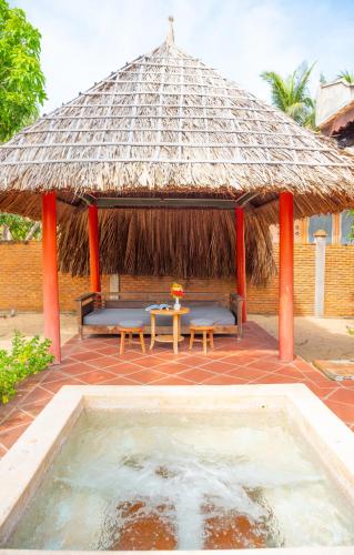 a pavilion with a table and chairs and a pool at Full Moon Village Resort in Mui Ne