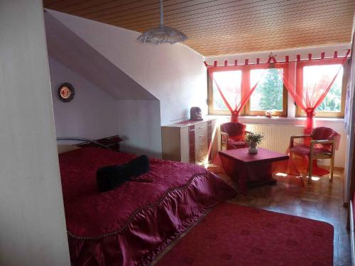 ein Schlafzimmer mit einem Bett, einem Tisch und zwei Fenstern in der Unterkunft Ferienwohnung Blütenmeer in Langenargen