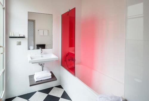 La salle de bains est pourvue d'un lavabo et d'un miroir rouge. dans l'établissement Hôtel Paris Vaugirard, à Paris