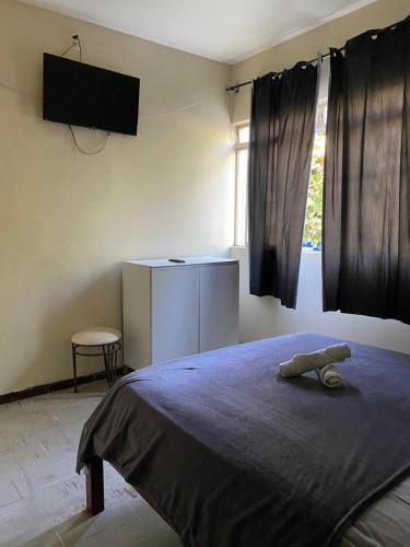 a bedroom with a bed with a tv on the wall at Quarto econômico central in Sete Lagoas