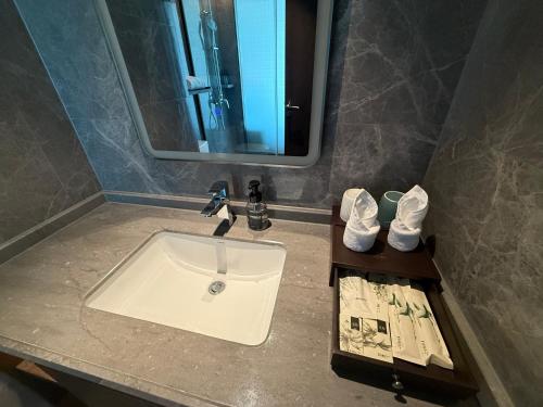a sink in a bathroom with a mirror and shoes at Till Bright Hotel, Foshan Shunde Ronggui Station Branch in Shunde