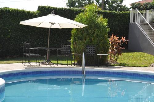 a pool with an umbrella and a table and chairs at Massive Cherry Garden Home in Cherry Garden