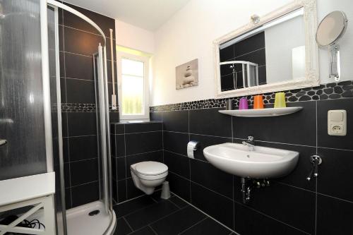 Un baño con lavabo, inodoro y espejo. en Taddel, en Norddeich