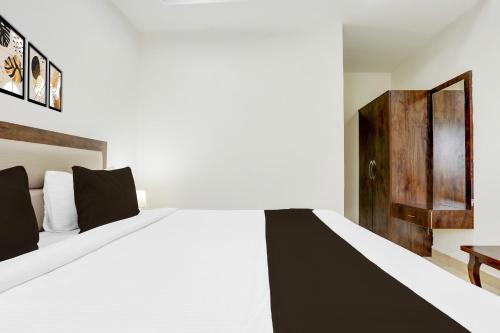 a bedroom with a white bed and a wooden door at Hotel O Aqua Comforts in Yelahanka