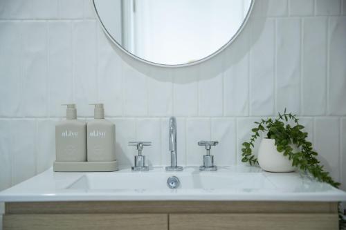 a bathroom sink with a mirror and a bottle of soap at El Parche Bilinga Beachside in Gold Coast