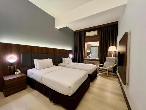 バトゥパハにあるThe Landmark Hotelのベッド2台と椅子があるホテルの部屋