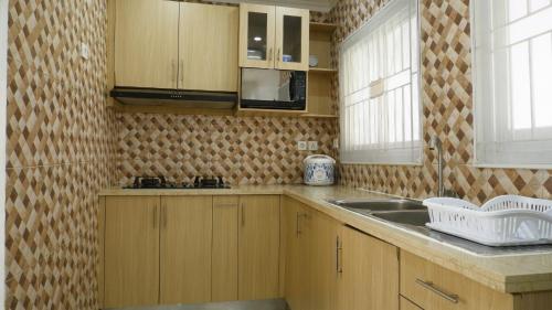 a kitchen with wooden cabinets and a sink at Diyar Villas Puncak K3/2A in Puncak