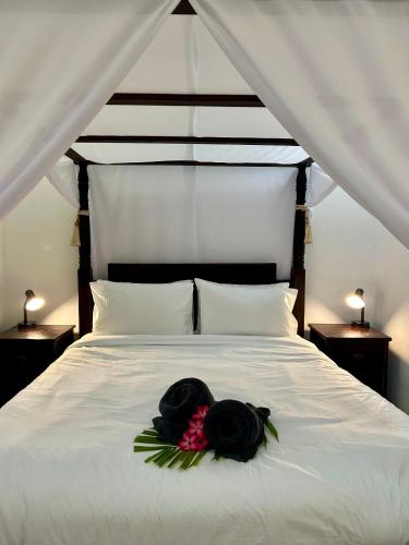 a white bed with two black hats on it at Will and Ray's at Lori Beach Inn in Seminyak