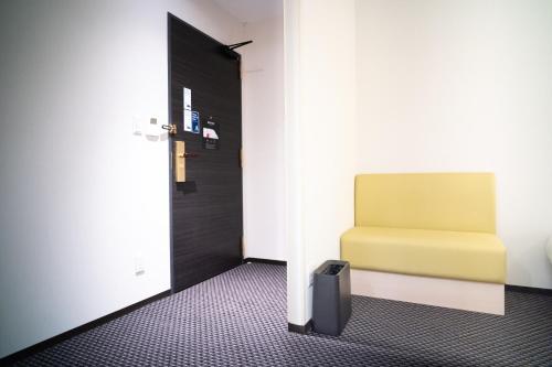 a room with a yellow chair and a door at KIORI Exec Gojo in Kyoto