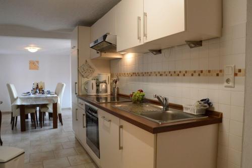 Una pequeña cocina con un fregadero y una mesa. en Bauernstube-Landhaus-Haan, en Norddeich