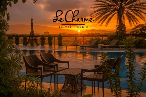 Una puesta de sol sobre una piscina con sillas y la Torre Eiffel. en Le Charmé Suites - Subic, en Olóngapo