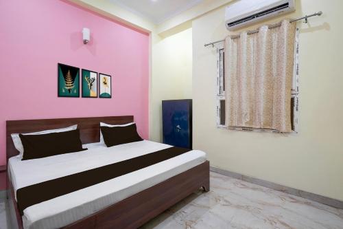 a bedroom with a bed and a pink wall at Hotel O BLISS INN in Chinhat