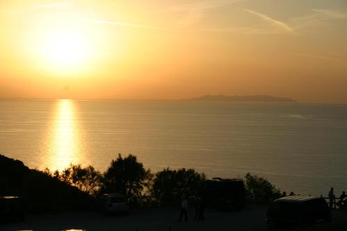 a sunset over the ocean with people walking on a hill at Agriturismo Podere San Michele in San Vincenzo