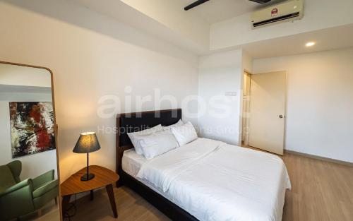 a bedroom with a white bed and a table with a lamp at Encorp Strand Residences by Airhost in Kota Damansara