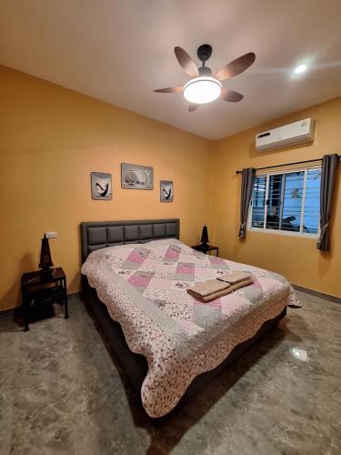 a bedroom with a bed and a ceiling fan at บ้านน้ำผึ้งโฮมสเตย์ in Suan Phung