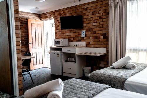 a hotel room with two beds and a desk and a tv at Buckaroo Motor Inn in Warwick