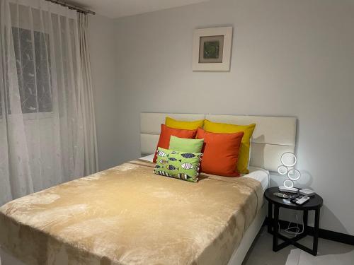 a bedroom with a bed with colorful pillows on it at Villa Paraiso do Mar in Jacó