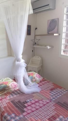 a bedroom with a bed with a white canopy at Grand volume meublé in Bouillante