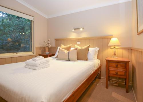 a bedroom with a large white bed with a window at Autumn Leaf Cottage 2 in Harrietville