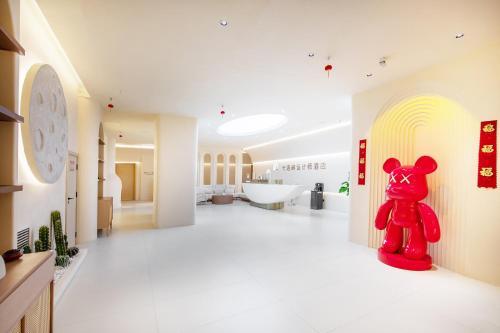 a red teddy bear sitting on the floor of a bathroom at Caroline Designer Hotel, Gaozhuang, Xishuangjing in Jinghong