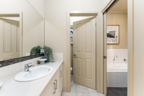 a bathroom with a sink and a mirror and a tub at Hinkler on the Lane - Stylish Coastal Escape in Victor Harbor