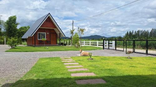 a dog laying on the grass in front of a house at บ้านน้ำผึ้งโฮมสเตย์ in Suan Phung