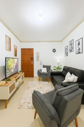 a living room with a couch and a tv at Apartamento próximo à praia, 500m da Praia dos Ingleses in Florianópolis