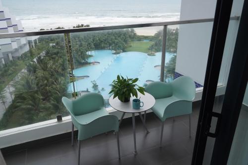 Cette chambre comprend une table et des chaises et offre une vue sur l'océan. dans l'établissement Havana Home at Arena Cam Ranh, à Cam Ranh International Airport