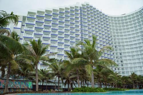 un grand bâtiment avec des palmiers devant dans l'établissement Havana Home at Arena Cam Ranh, à Cam Ranh International Airport