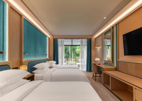 a hotel room with four beds and a flat screen tv at Dusit Thani Krabi Beach Resort in Klong Muang Beach