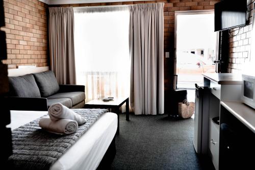 a hotel room with a bed with a towel on it at Buckaroo Motor Inn in Warwick