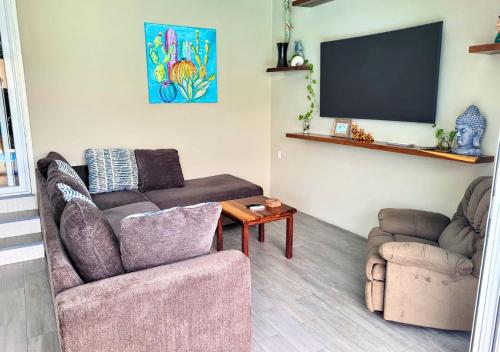 a living room with a couch and a tv at Casa Cactus - 2-Story Home with Garden and Pool in Puerto Escondido