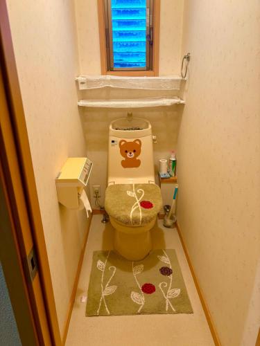 a small bathroom with a toilet with a teddy bear on the lid at 覚羅中央区別荘202室 in Chiba