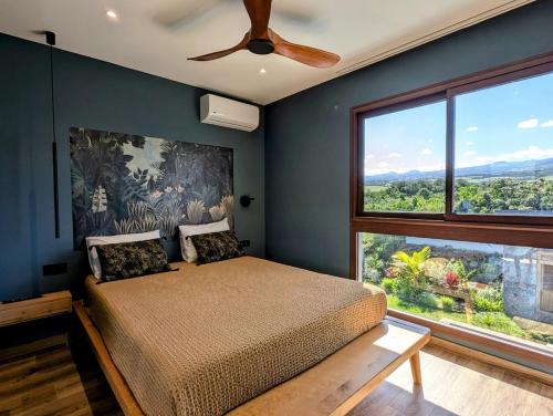 une chambre avec un lit et un ventilateur de plafond dans l'établissement La villa Blue Banian, à Saint-Pierre