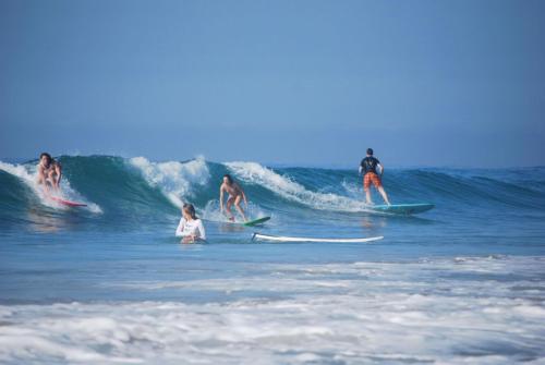 un grupo de personas montando una ola en tablas de surf en el océano en Bayview Seafood rest, en Weligama