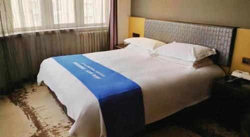 a bedroom with a large bed with a blue and white blanket at Harbin Splendent Hotel in Harbin