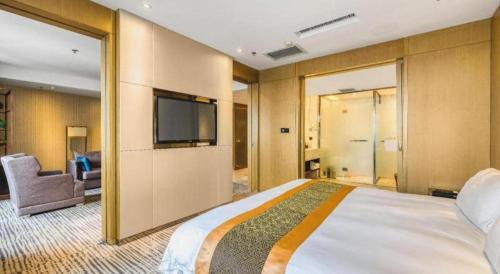 a hotel room with a large bed and a flat screen tv at Harbin Splendent Hotel in Harbin