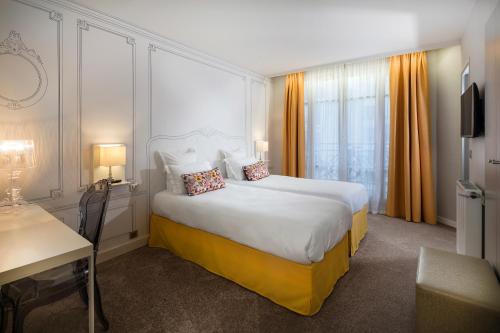 a hotel room with a large bed and a desk at Hôtel Paris Vaugirard in Paris