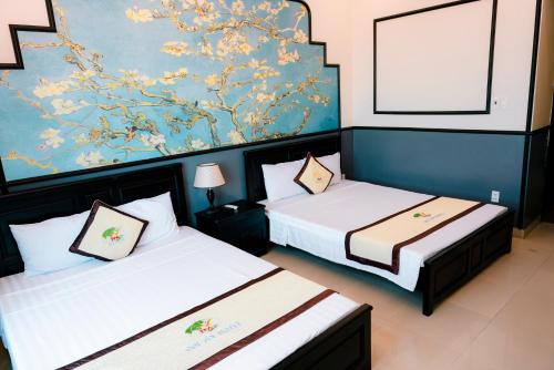 two beds in a room with a painting on the wall at Khách sạn Đại An Ninh Bình in Ninh Binh