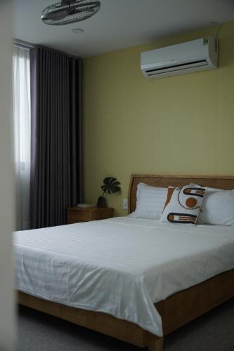 Cette chambre comprend un grand lit avec des draps blancs et un ventilateur. dans l'établissement Kim Homestay in Hue, à Thôn Lại Thê