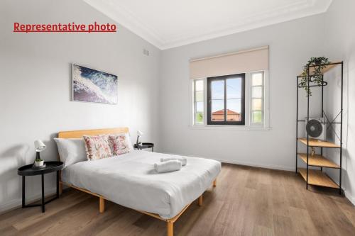 a white bedroom with a bed and a window at Affordable Double Bedroom - Heart of Belmore with Shared Bathroom in Sydney