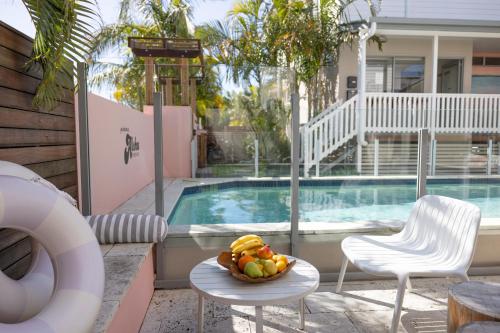 a bowl of fruit on a table next to a swimming pool at Aloha Byron Bay in Byron Bay