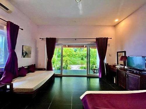 a bedroom with a bed and a tv and a window at Terrace Resort in Phu Quoc