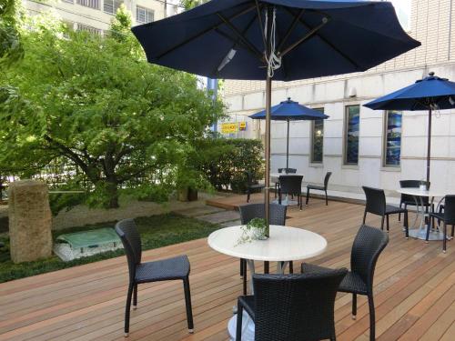 a patio with tables and chairs with blue umbrellas at Meitetsu Inn Nagoya Kanayama in Nagoya